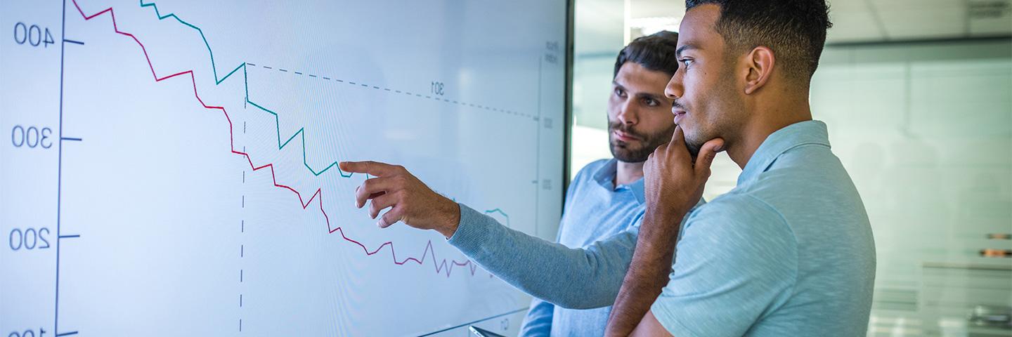 Two business people looking at financials on a monitor