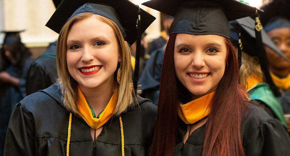 两个学生戴着毕业帽，穿着毕业服